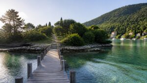 A wooden dock leading to a quiet green island cove with clear water and distant village houses